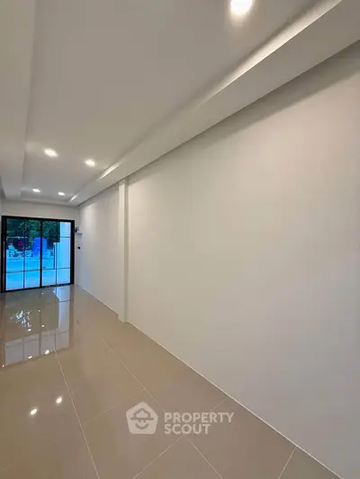 Spacious modern living room with glossy tiled floors and large windows.