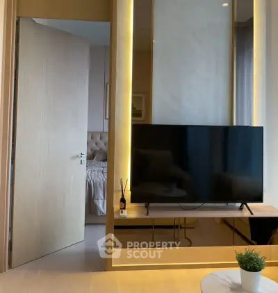 Modern living room with sleek TV setup and open door to cozy bedroom