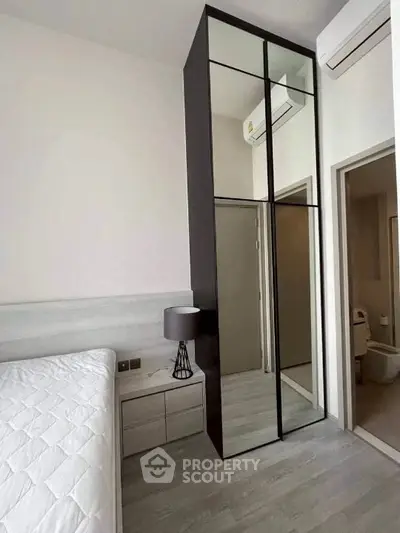 Modern bedroom with mirrored wardrobe and air conditioning unit