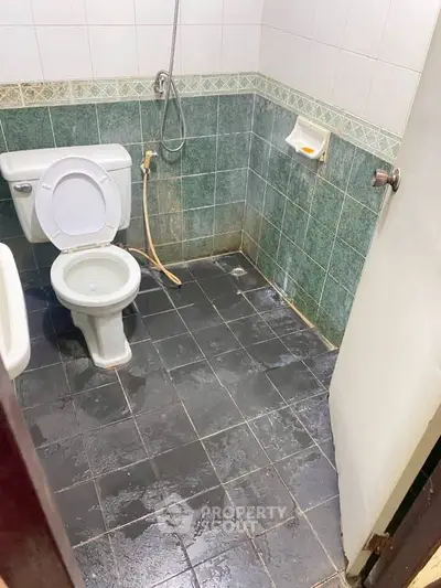 Basic bathroom with tiled floor and walls, featuring a toilet and shower area.