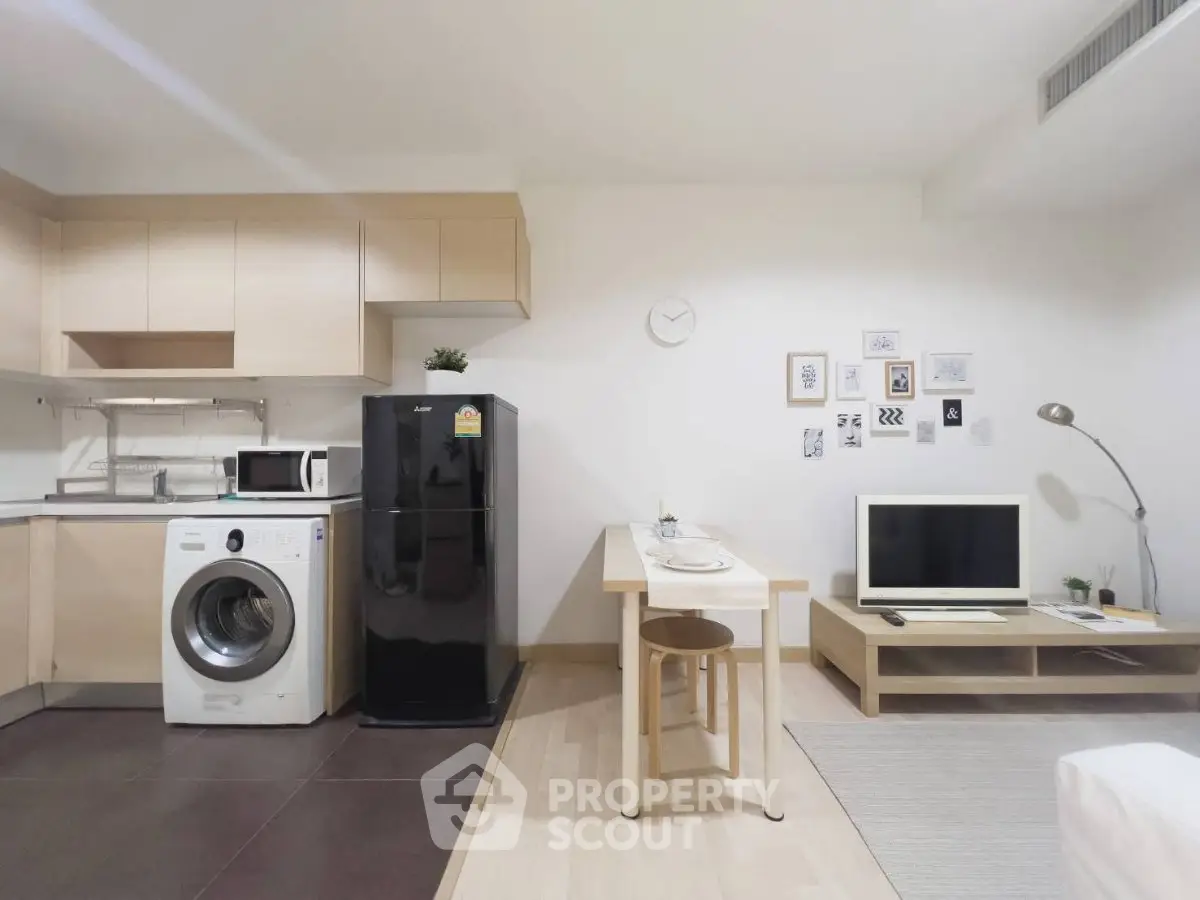 Modern studio apartment with open kitchen, washing machine, and cozy living area.