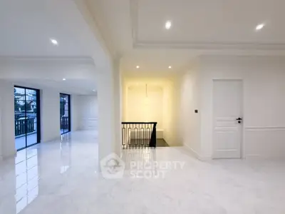 Spacious modern living area with elegant white interiors and large windows for natural light.