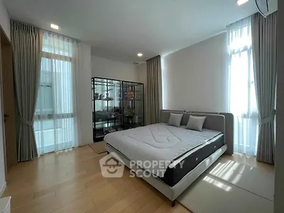 Spacious bedroom with modern decor and large windows for natural light.
