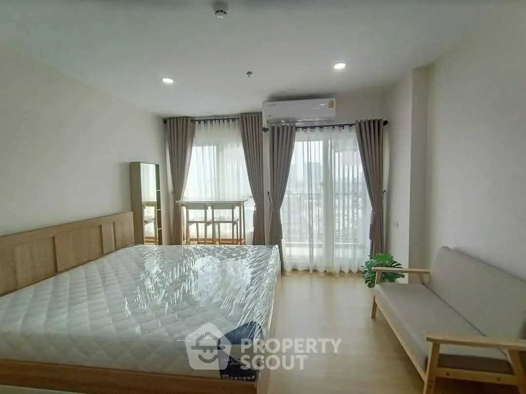 Spacious bedroom with large windows and modern furnishings in a bright apartment.