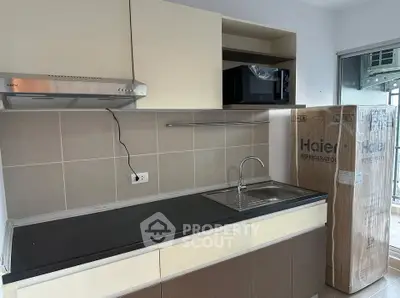 Modern kitchen with sleek cabinetry and new appliances, featuring a Haier refrigerator and built-in microwave.