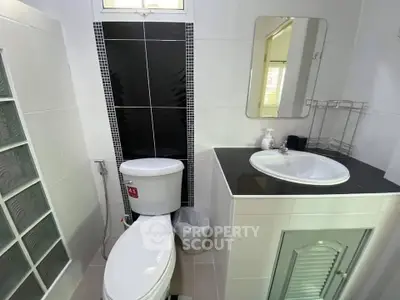 Modern bathroom with sleek black and white tiles, featuring a stylish sink and toilet.