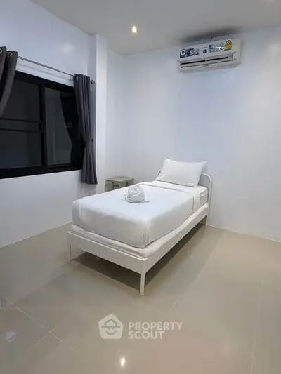 Minimalist bedroom with single bed and air conditioning, perfect for a cozy and comfortable living space.