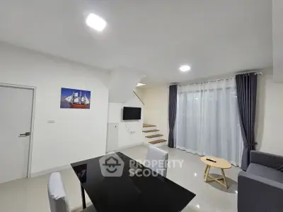 Modern living room with sleek furniture and staircase, featuring a minimalist design and ample natural light.
