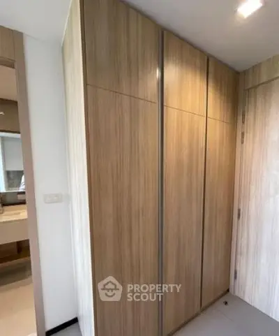 Modern interior with sleek wooden storage cabinets and glimpse of a stylish bathroom.
