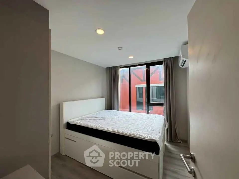 Modern bedroom with large window and minimalist design in urban apartment.