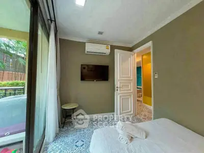 Cozy bedroom with modern decor, air conditioning, and a view of the garden through large windows.