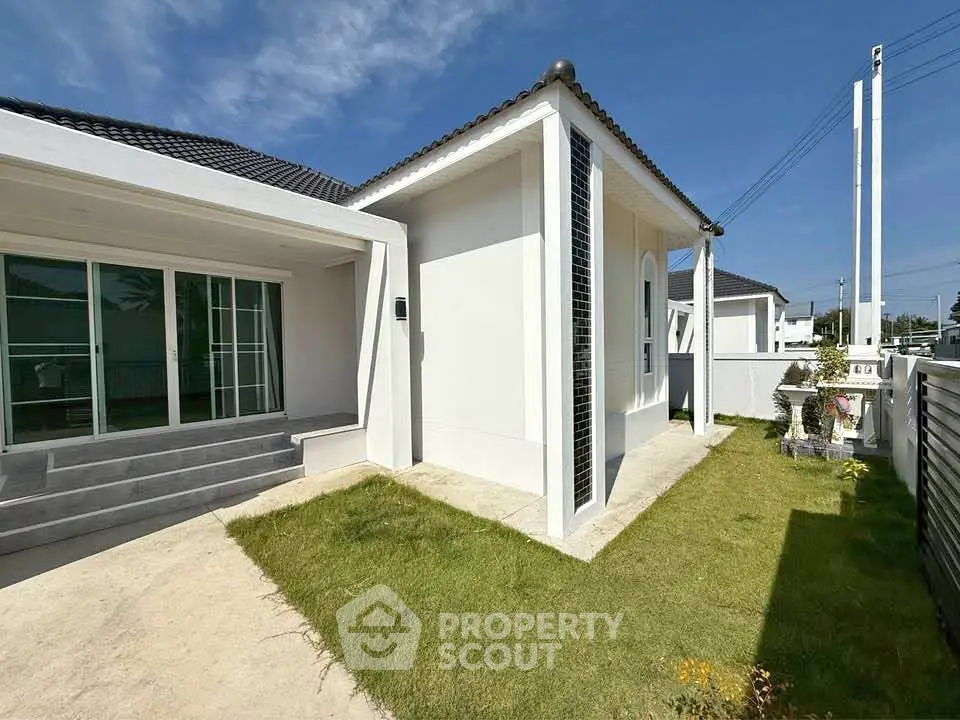 Modern white house exterior with lush green lawn and clear blue sky
