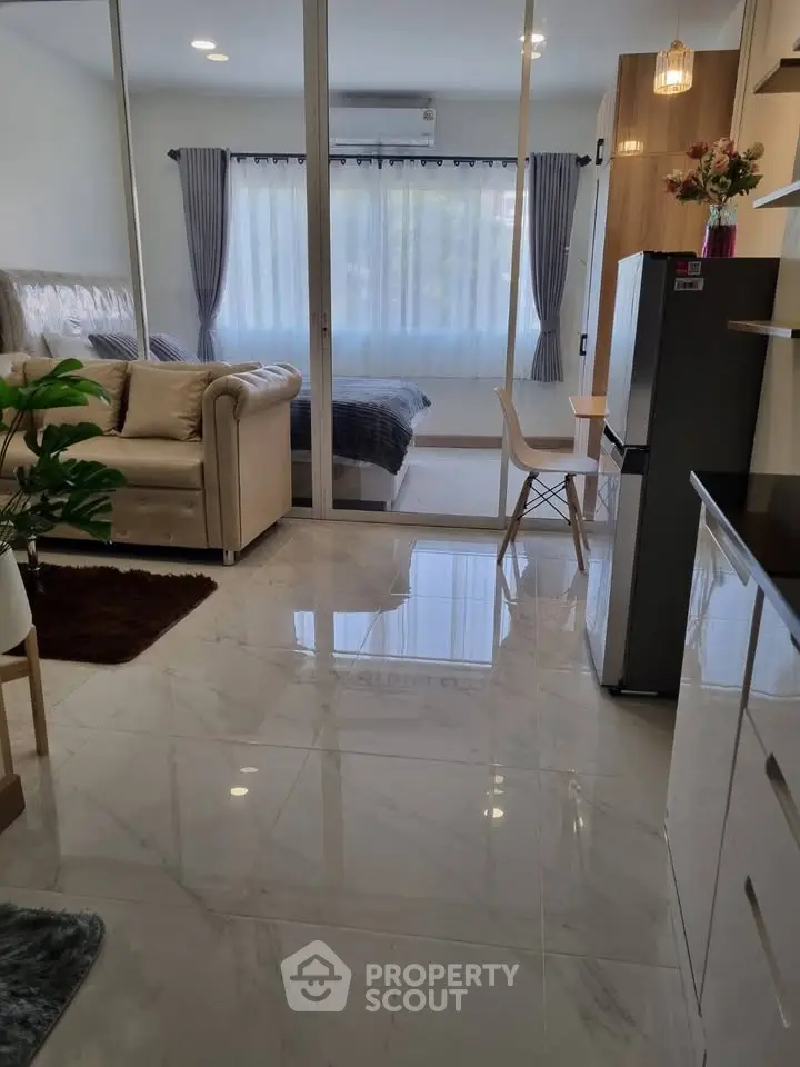 Modern open-plan living room with sleek kitchen and cozy bedroom view.