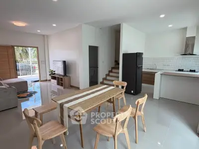 Spacious modern living room with open kitchen and dining area, featuring sleek furniture and natural light.