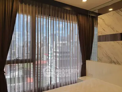 Luxurious bedroom with stunning city view through elegant sheer curtains.