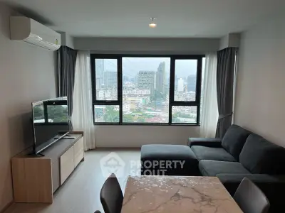 Modern living room with city view, featuring sleek furniture and large windows.