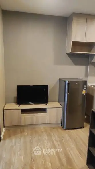 Modern living room with sleek TV stand and compact fridge, perfect for urban living.