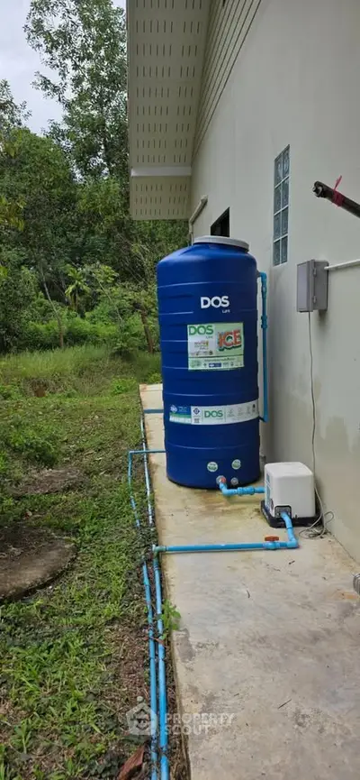 Outdoor water tank installation next to a residential building, showcasing efficient water management system.