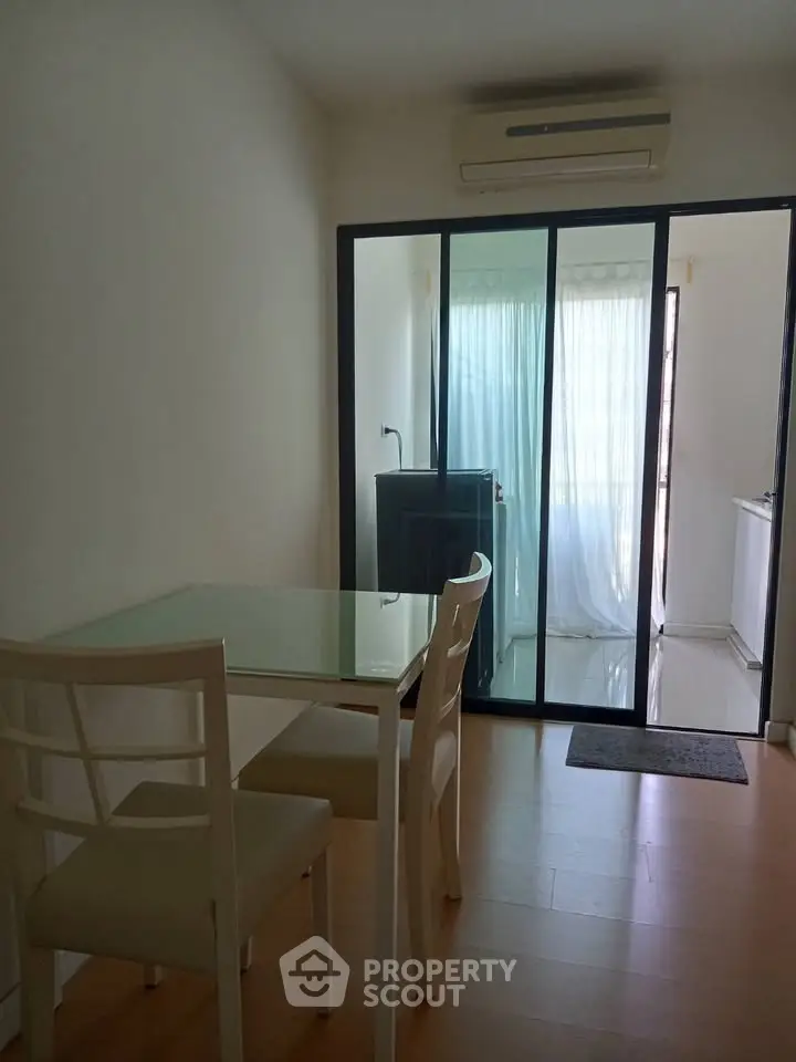 Modern dining area with glass table and sliding doors leading to a bright balcony.