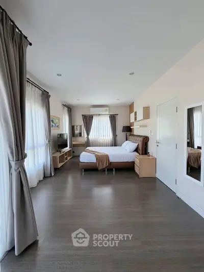 Spacious modern bedroom with elegant decor and large windows for natural light.