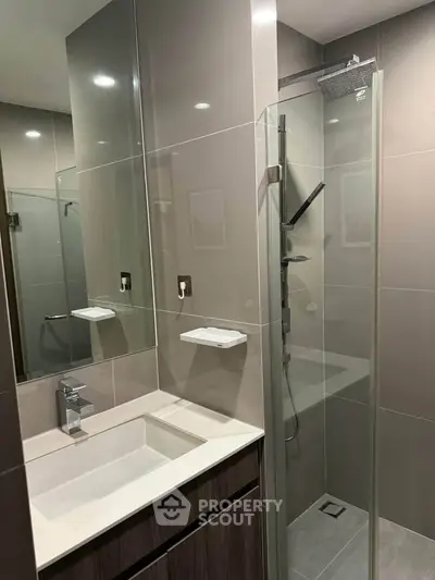 Modern bathroom with sleek glass shower and stylish vanity in contemporary apartment.