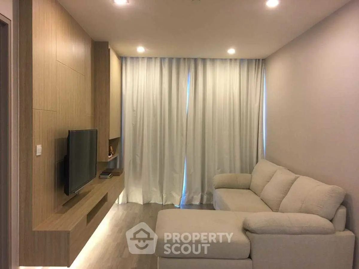 Modern living room with cozy sofa and wall-mounted TV, featuring elegant lighting and wooden accents.