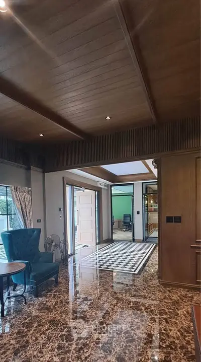 Luxurious living room with marble flooring and elegant wooden ceiling, showcasing modern interior design.