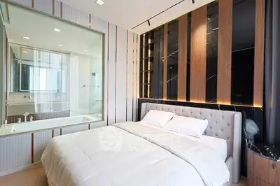 Luxurious modern bedroom with elegant decor and glass wall bathroom view.