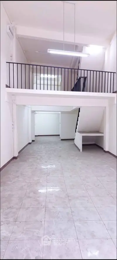 Spacious loft-style interior with mezzanine and tiled flooring, ideal for creative workspace or modern living.