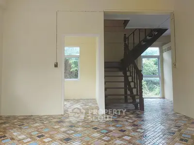 Spacious interior with unique tiled flooring and wooden staircase, bright natural light.