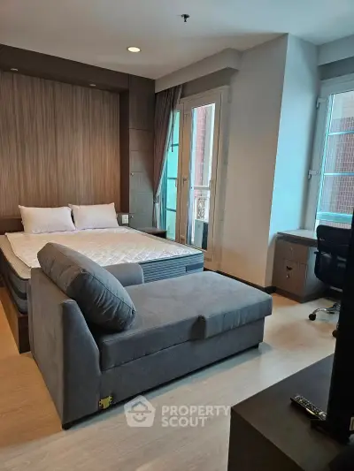 Modern studio apartment with cozy bed and stylish sofa in a bright, well-lit room.