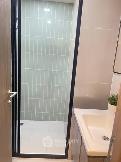 Modern bathroom with sleek shower and stylish sink in contemporary apartment.