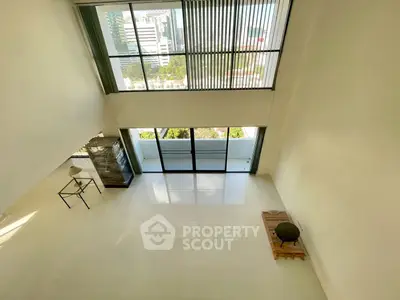 Spacious modern living room with floor-to-ceiling windows and balcony view.