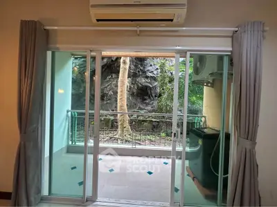 Charming apartment with balcony overlooking lush greenery and modern air conditioning.