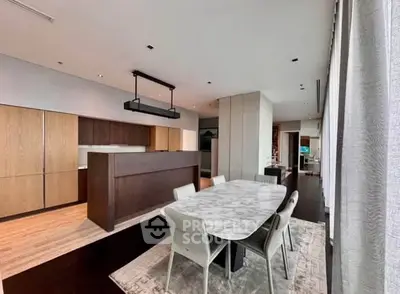 Luxurious modern kitchen with open layout and elegant dining area, featuring sleek cabinetry and marble dining table.