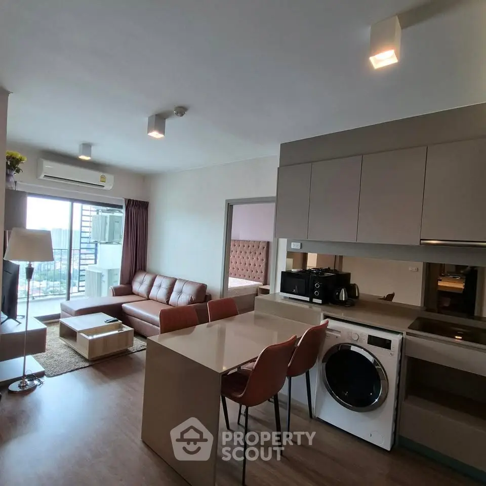 Modern open-plan living room with kitchen, featuring stylish furniture and appliances, ideal for urban living.