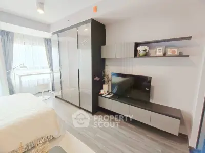 Modern bedroom with sleek wardrobe and entertainment unit, featuring stylish decor and natural light.