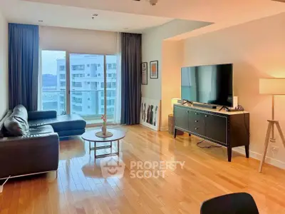 Spacious modern living room with hardwood floors and large windows offering city views.