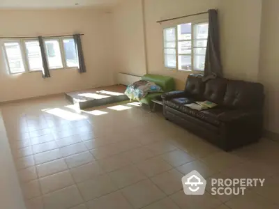 Spacious living room with tiled flooring and large windows for natural light.