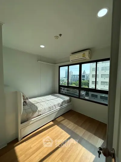 Bright bedroom with city view, featuring a single bed and air conditioning, perfect for urban living.