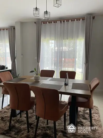 Elegant dining area with modern table and chairs, natural light through large windows, perfect for gatherings.