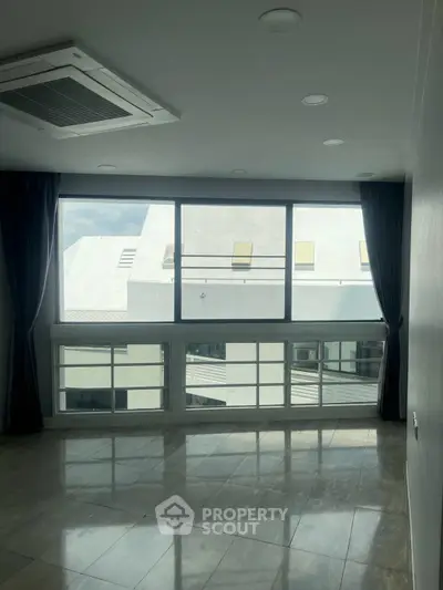Spacious room with large windows offering abundant natural light and modern ceiling design.