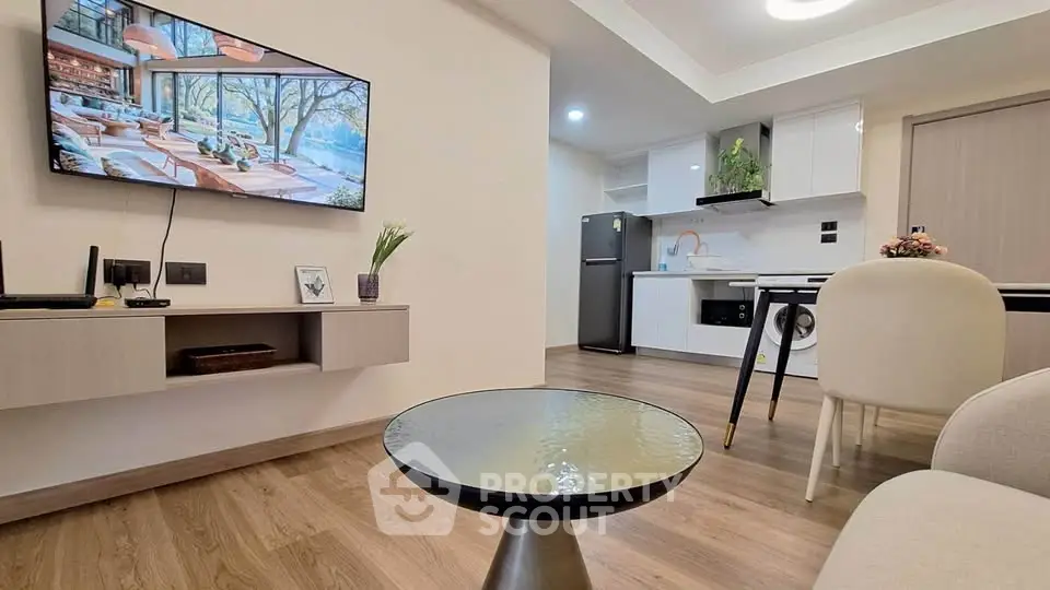 Modern living room with open kitchen, featuring sleek furniture and wooden flooring.