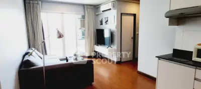 Modern living room with sleek furniture and open kitchen layout, featuring natural light and stylish decor.