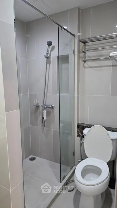 Modern bathroom with glass shower enclosure and sleek fixtures in a contemporary apartment.