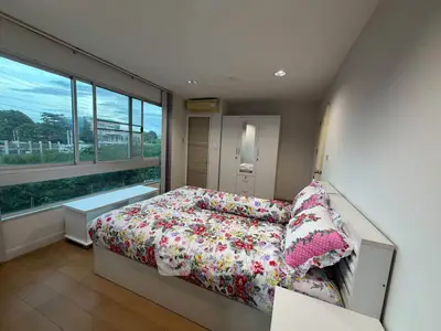 Spacious bedroom with large window and floral bedding, offering serene views and ample natural light.