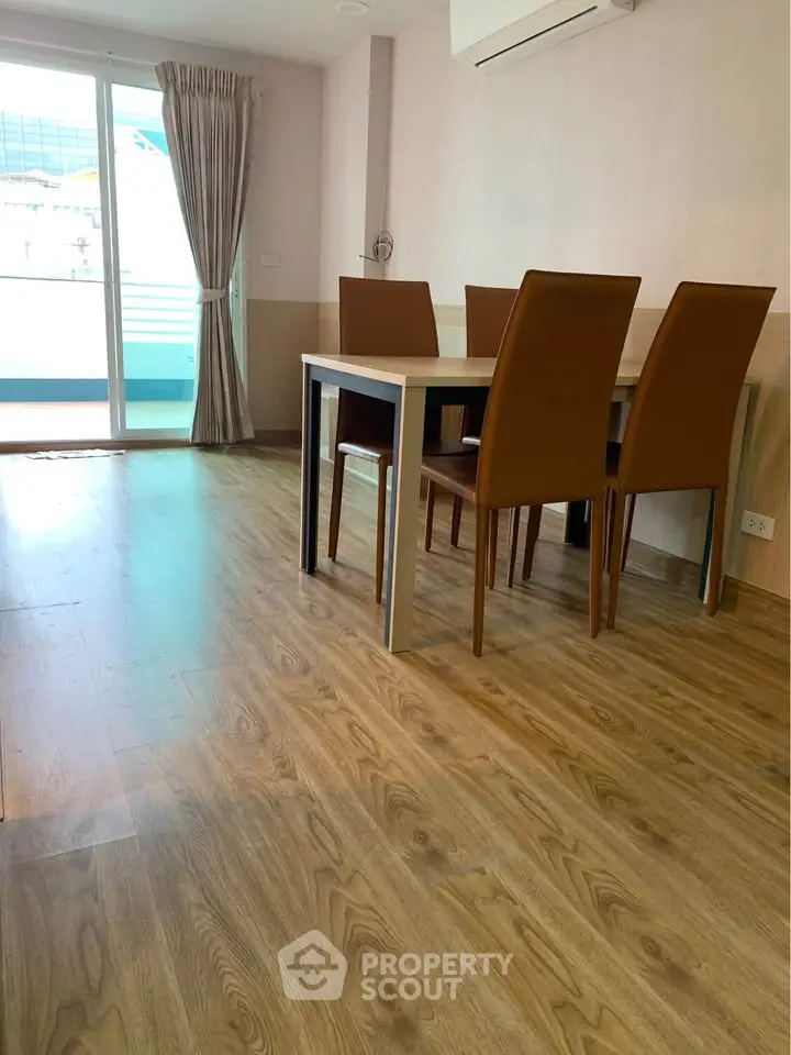 Modern dining area with wooden flooring and elegant chairs near a balcony.