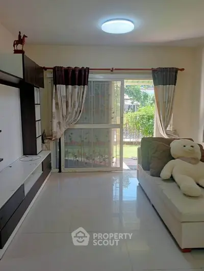Bright living room with sliding glass doors and plush teddy bear on sofa