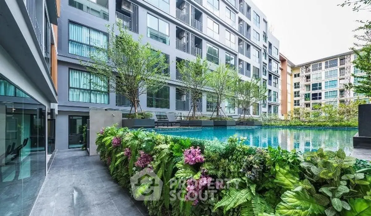 Modern apartment complex with lush garden and inviting pool area.