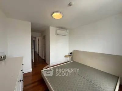 Spacious bedroom with wooden flooring and modern air conditioning unit.